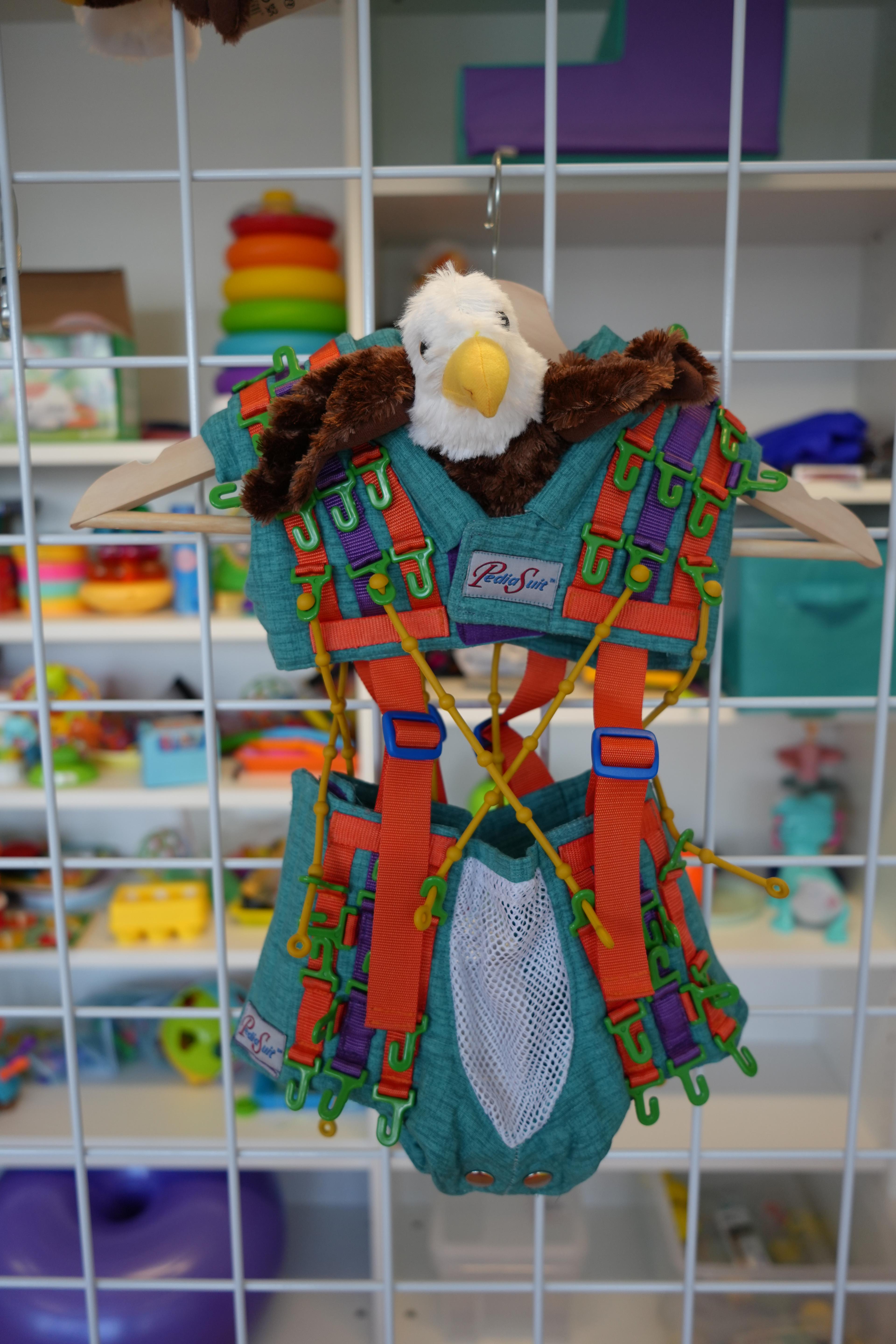 An eagle plushie wearing the PediaSuit — our quiet brand mascot