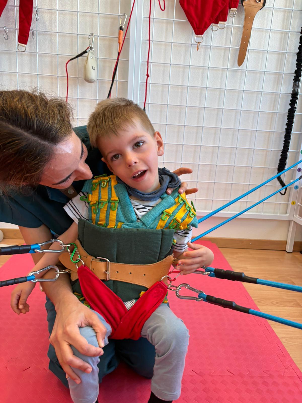 Therapist guiding Charlie through a sensophysio session in the harness rig at our Zug centre